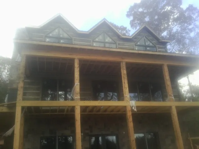 Dormers and porch framing on a large log home under construction — Roof Coating work by our crew in Delmar
